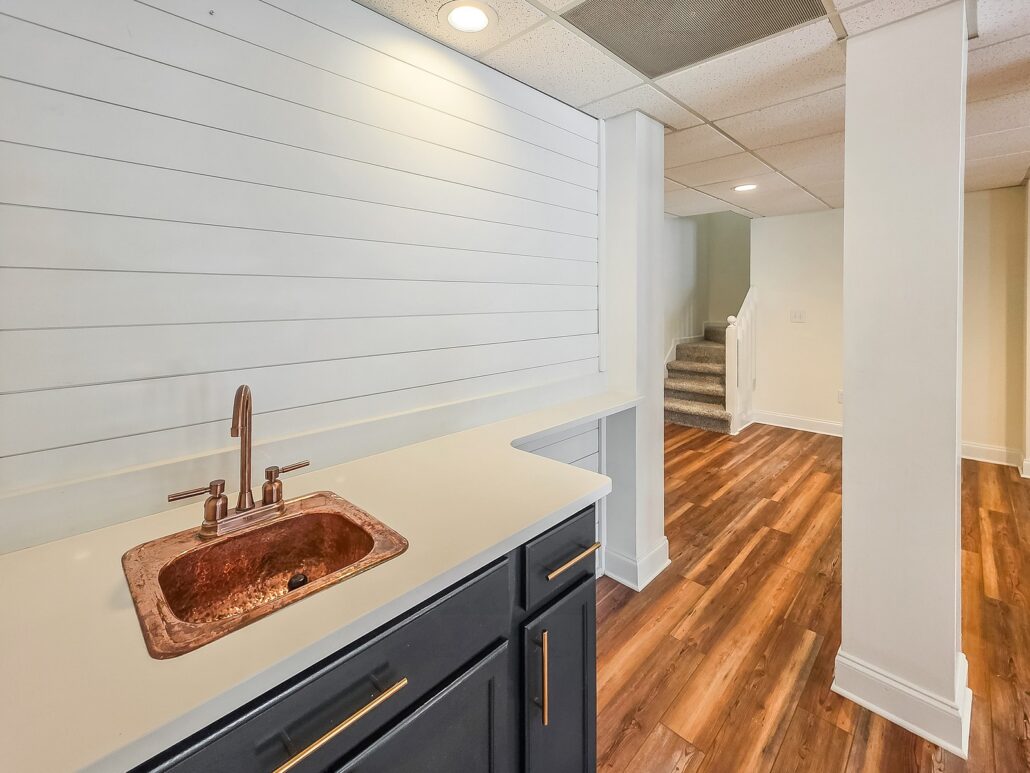 Basement wet bar with a hammered copper sink, charcoal cabinets and a shiplap wall at 1030 Billy Mantle Lane