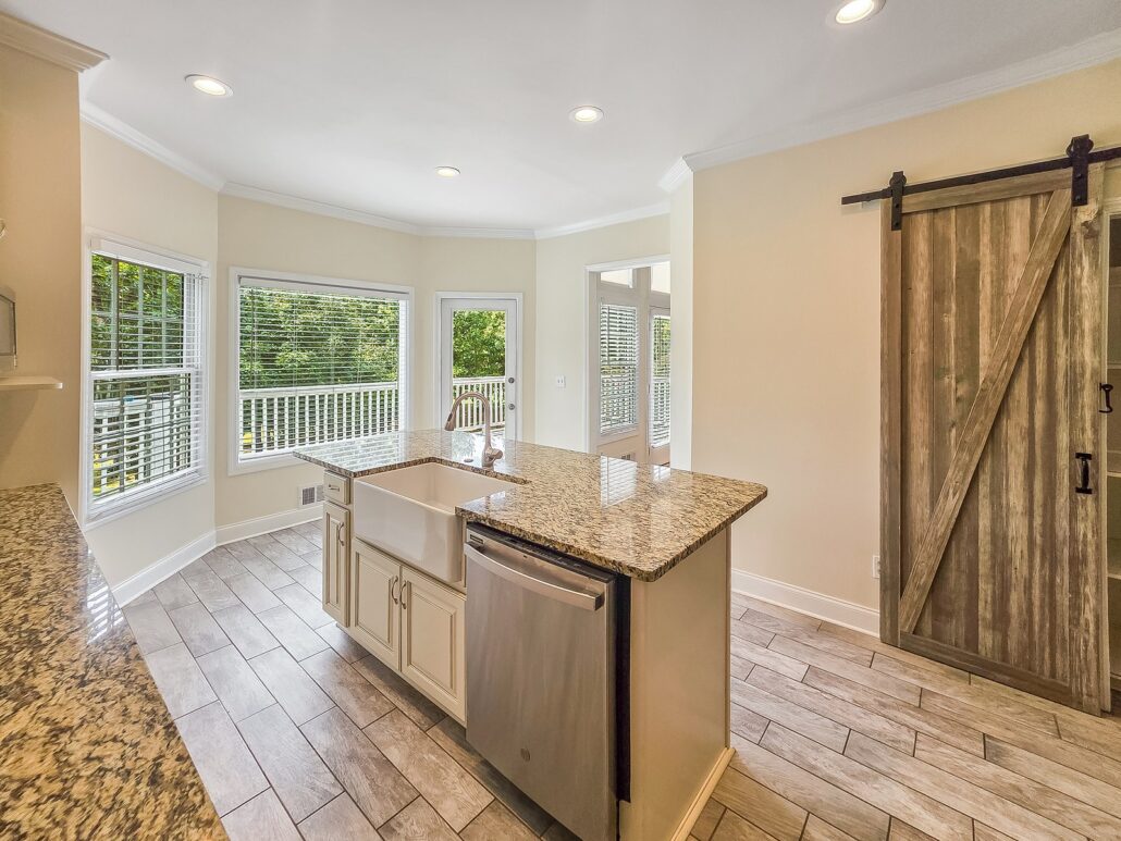 Breakfast room with bay windows and a door to the deck, beside the kitchen island and barn-door pantry, at 1030 Billy Mantle Lane