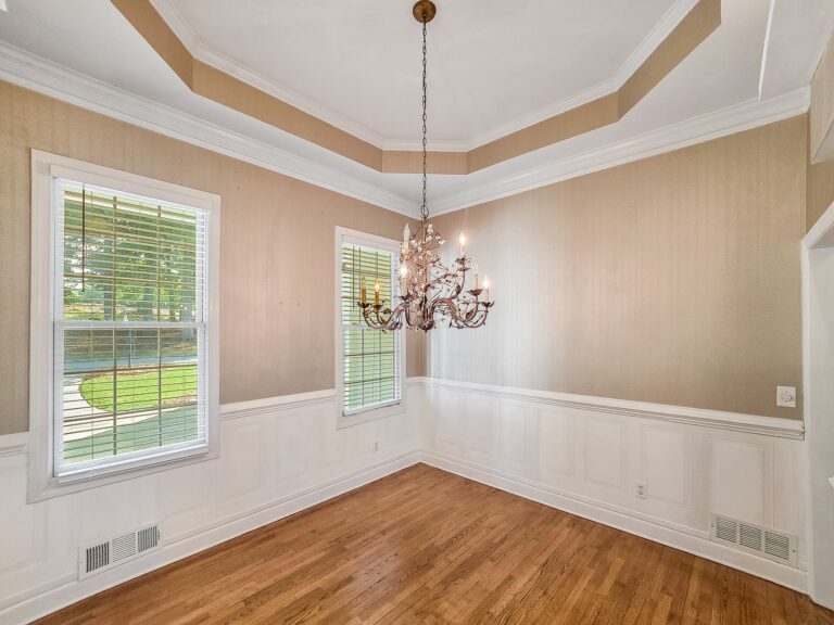 Dining room with wainscoting, a tray ceiling and windows to the front yard at 1030 Billy Mantle Lane