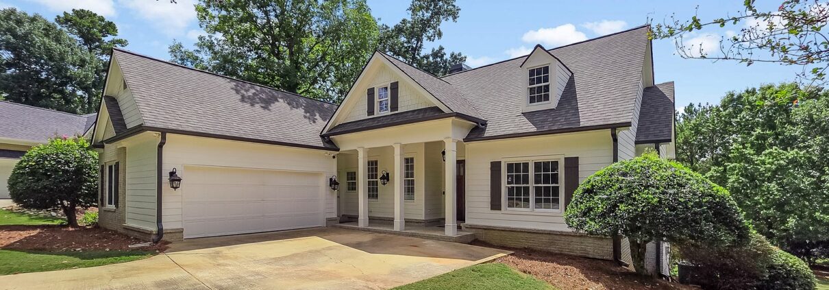 The front of 1030 Billy Mantle Lane in Harbor Club on Lake Oconee, Georgia, with a covered porch and attached two-car garage