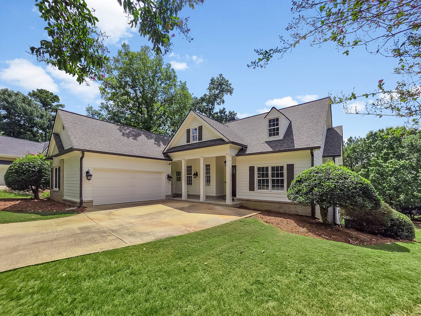The front of 1030 Billy Mantle Lane in Harbor Club on Lake Oconee, Georgia, with a covered porch and attached two-car garage
