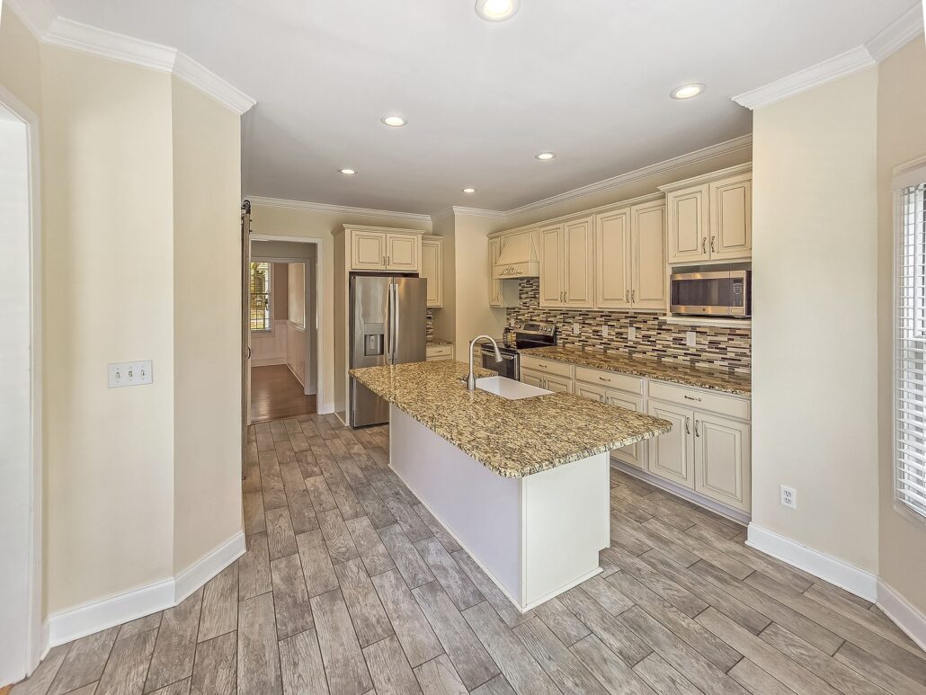 Kitchen at 1030 Billy Mantle Lane with cream cabinets, granite counters, a mosaic tile backsplash and stainless appliances