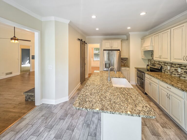 Granite kitchen island with a farmhouse sink, open to the living room, at 1030 Billy Mantle Lane