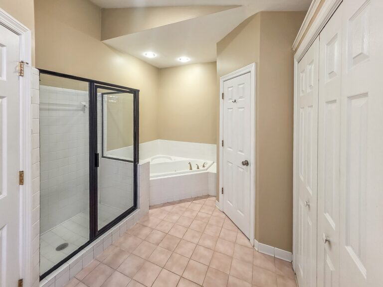 Primary bathroom with a glass-enclosed shower, corner tub and double closet at 1030 Billy Mantle Lane