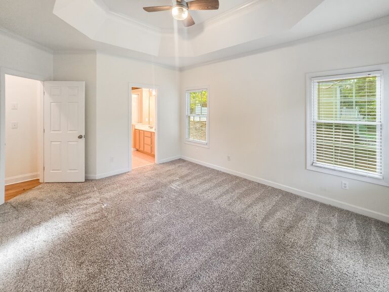 Primary bedroom with a tray ceiling and a door to the bath at 1030 Billy Mantle Lane