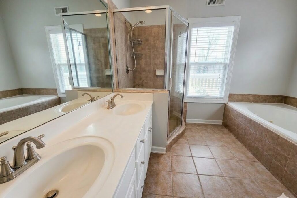 Primary bathroom with a double vanity, glass-enclosed shower and garden tub in an Eatonton townhome on Lake Oconee