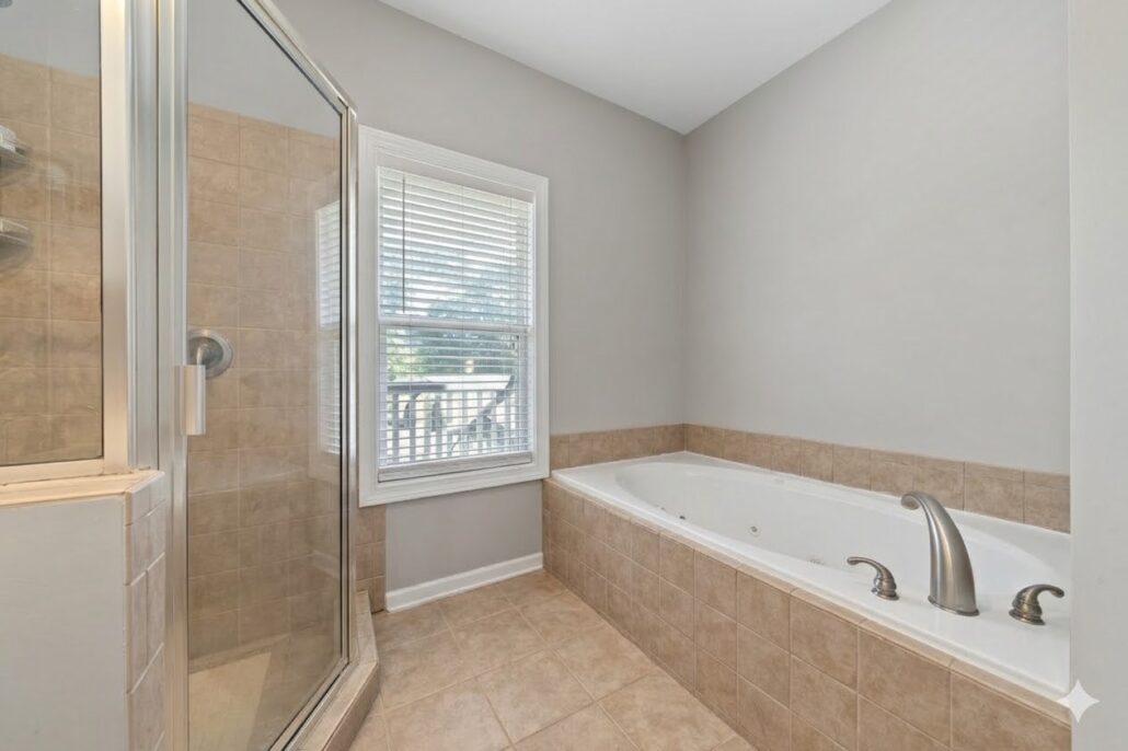 Garden tub beneath a window beside the glass shower in the primary bath of a condo on Lake Oconee
