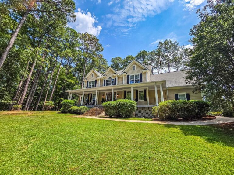 2750 Club Drive seen from the lawn, showing the full front elevation and mature pines in Harbor Club