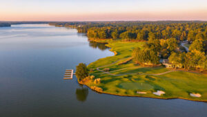 Aerial view of waterfront luxury real estate, a private boat dock, and a golf course green at Lake Oconee Georgia