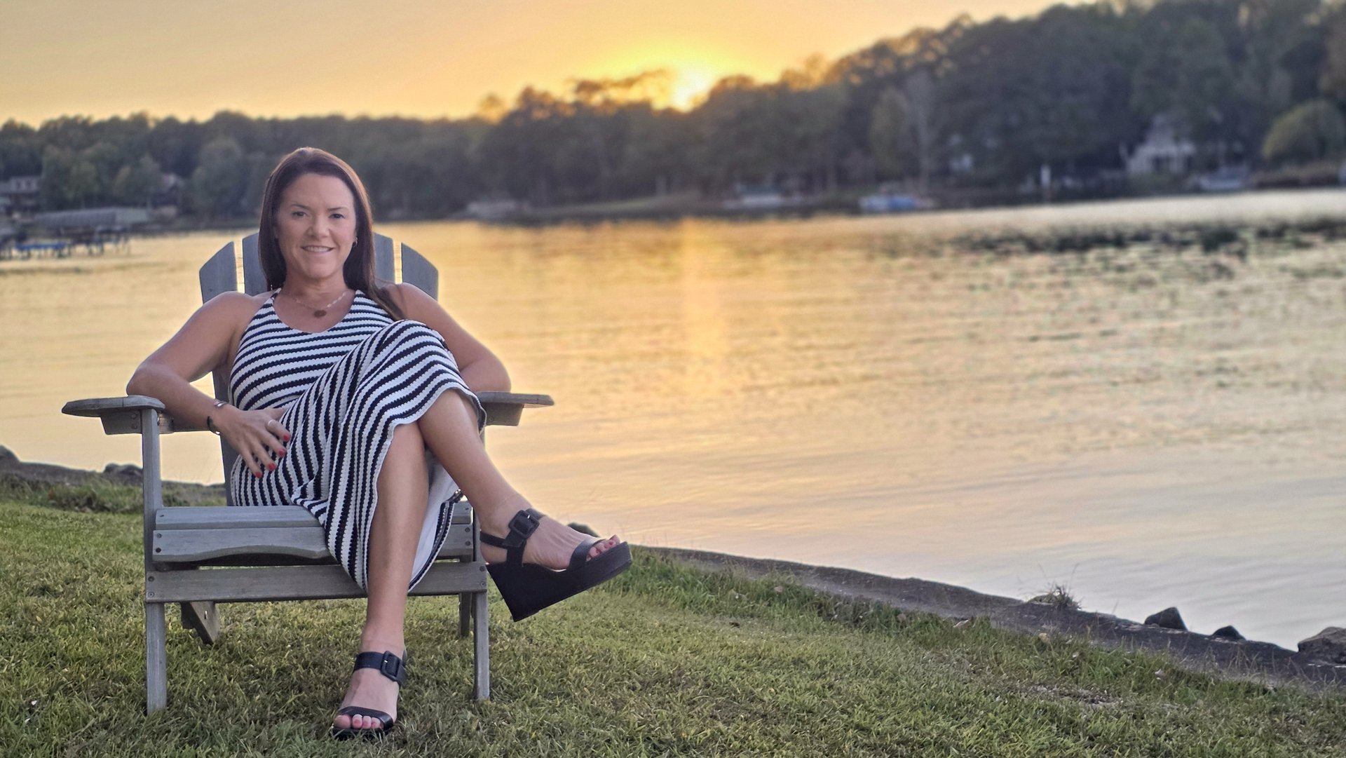 Margie Sorrell, Lake Oconee REALTOR, in an Adirondack chair on the Lake Oconee shoreline at sunset