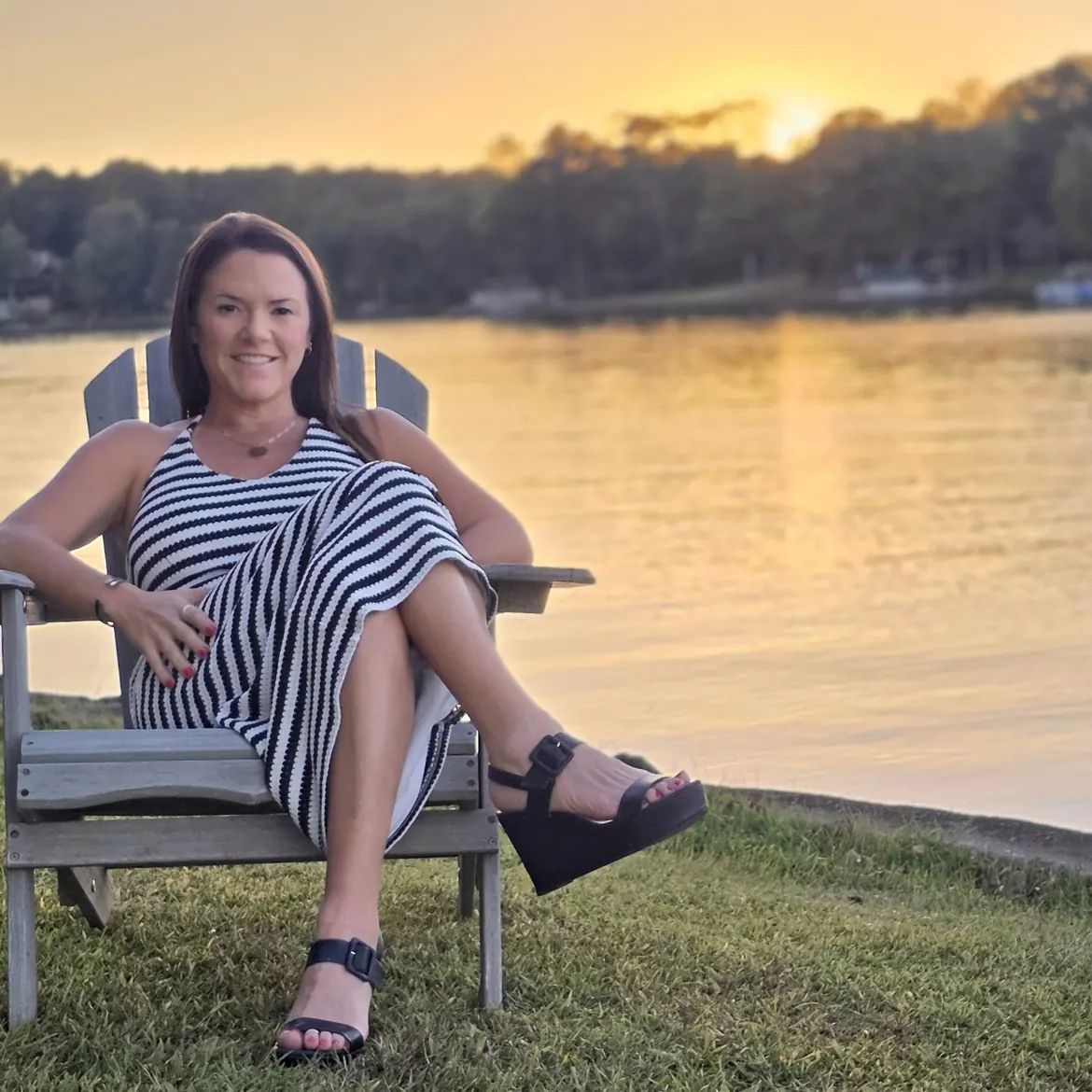 Margie Sorrell, Lake Oconee REALTOR, in an Adirondack chair on the Lake Oconee shoreline at sunset